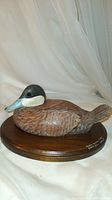 Side angle of the decoy showing the full body and painted details, mounted on a wooden base.