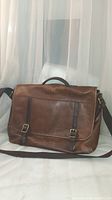 Front view of brown leather messenger bag with buckle straps and shoulder strap