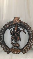 Front view of large Ganesh sculpture enclosed in a circular frame with floral decorations and a face design at the top.