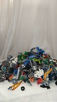 Wide shot of numerous Lego Bionicle figures and parts piled together showing various colors and components.