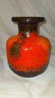 Front view showing bright orange lava glaze and dark brown-black accents on vase body and neck.