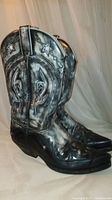 Side profile showing the black and white leather cowboy boots with star designs on the shaft and detailed stitching.