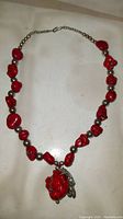 Full view of red turquoise style necklace arranged in a circle showing chunky red beads, silver ball spacers, and central pendant.