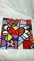 Top view showing colorful pop art heart plate with geometric patterns.