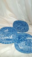 Three blue and white Rorstrand Christmas plates together showing detailed festive Scandinavian scenes.