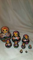 Nine handpainted wooden babushka nesting dolls arranged in descending size order on white cloth background