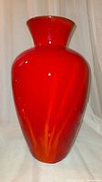 Front view of tall red flared vase with orange sun stripe near base