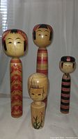All four Kokeshi dolls shown together highlighting size and design differences.
