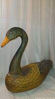 Front view of hand carved and painted wood swan goose bird figurine showing detailed neck and head with orange beak and yellow body.