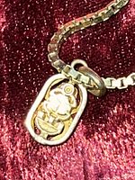 Close-up of pendant showing cut-out floral motif within oval frame