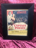 Full view of the framed Captain Pirate movie poster against a pink fabric background showing the colorful illustration and typography.