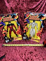 Both Marvel Universe figurines Captain Marvel and Moon Knight displayed in original packaging with a measuring tape showing scale, set on red velvet background.