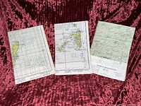 Three large vertical aeronautical/topographical maps on red fabric background, showing grid lines and geographic regions.
