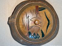 Top view of the interior of the wooden bowl showing the painted design with Japanese motifs in red, green, and brown with a circular knob in the center.