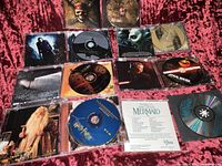 Photo showing the 5 CDs laid out on a red fabric background, including discs and cover art visible with Star Wars, Harry Potter, The Little Mermaid, Pirates of the Caribbean.