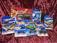 Photo showing lot of Hot Wheels and Johnny Lightning cars in original packaging, including commemorative boxed set and various blister card cars