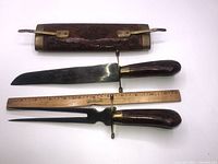 Photo showing meat carving knife, carving fork, wooden sheath, and measuring ruler for scale.