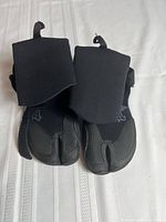 Top view of the pair of black wetsuit booties showing overall shape, size, and wide opening flaps.