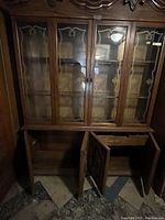 Full front view of the wooden china cabinet showing four glass doors on top and two wooden doors open at the bottom.