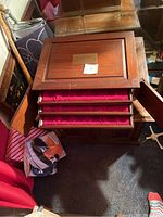 Photo showing front view of the wooden coin holder with drawers open revealing red fabric lining.