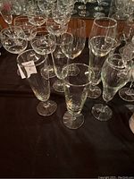 Photo showing 13 clear glasses on a black cloth, including champagne flutes, wine glasses, and mixed glassware.