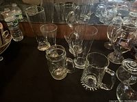Photo showing various clear glassware including pitchers, tumblers, and a square patterned beer mug