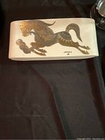 Closed view of rectangular ceramic box with stylized galloping horse design on lid