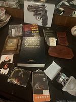 Photo of mixed items on tabletop including books, phone cases, leather goods, a screen protector, plaque, and baseball card in display case