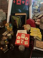 Front view of assorted items including piggy banks, figurines, CDs, books, match sticks, and jewelry box