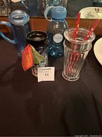 Photo showing four Starbucks drinking items arranged side by side including a French press, travel mug, water bottle, and frappe cup with straws.