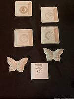Two sets of four square J Summers Greek key mini trays and two butterfly-shaped dishes each displayed on black background with lot number card.