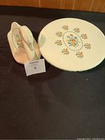 Full view of two-piece ceramic set including round plate and swan holder on black surface.