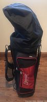 Full view of Augusta black golf bag with red trim and detachable cover closed