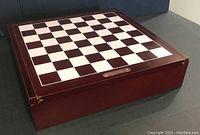 Closed wooden rectangular game case with checkered chessboard on top