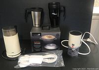 Full lot of kitchen appliances and accessories, including boxed pudding steamer, coffee grinder, chopper, extension cord, and two travel mugs