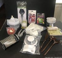 Photo showing Pampered Chef Manual Food Processor, Burger & Slider Press, Mini Salad Spinner, Ravioli Press set, garlic-related tools, hand grater, FoxRun cheese slicer, Rosti kitchen tools, produce saver accessories, and opener set.