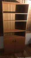 Frontal view of teak-finish MDF bookcase showing four open shelves and lower cabinet with two doors and rounded handles