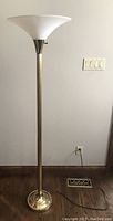Upright standing brass lamp off, showing body and shape.