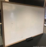 Whiteboard surface with visible minor scratches and wooden frame edge.