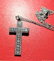 Front view of cubic zirconia cross pendant and chain on a red background.