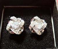 Close-up image of two stud earrings in black box background showing detailed arrangement of cubic zirconia stones in knot style and sterling silver setting.