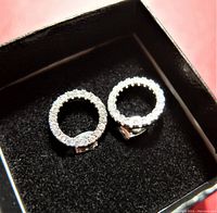 Pair of circular hoop earrings with faceted cubic zirconia stones set around the edge, shown front-facing in black fabric box.
