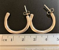 Pair of sterling silver hoop earrings on a black background with a measuring ruler showing length about 3.5 cm