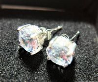 Close-up photo of the pair of sterling silver stud earrings with faceted round cubic zirconia stones against a black background.