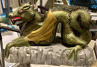 Side view of the vintage dragon table lamp with detailed scales and curled tail on a rock base.