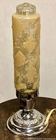 Full view of lamp showing apricot floral bullet-shaped glass shade and chrome-tone metal base on dark surface.