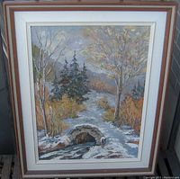 Frontal image of the framed oil painting depicting a stone bridge over a stream with autumn trees in the background.