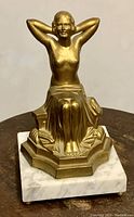 Front view of the seated bronze statue with white marble base