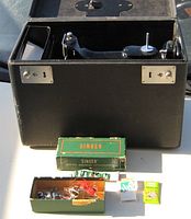 Accessories box contents with extra feet, bobbins, screwdriver and packets of needles