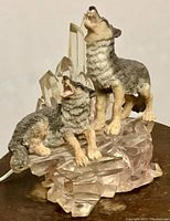Front angle of the non-illuminated wolf pair table lamp showing detailed wolf figures and clear acrylic base.
